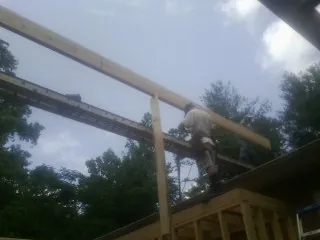 Carpenter setting a ridge beam over a new addition frame — Ice Dam Removal by Roofing Brothers in Lamy