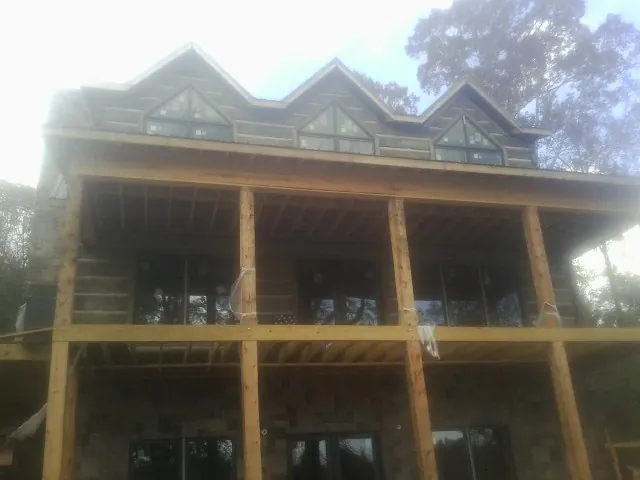 Dormers and porch framing on a large log home under construction — Roof Coating work by our crew in Lamy